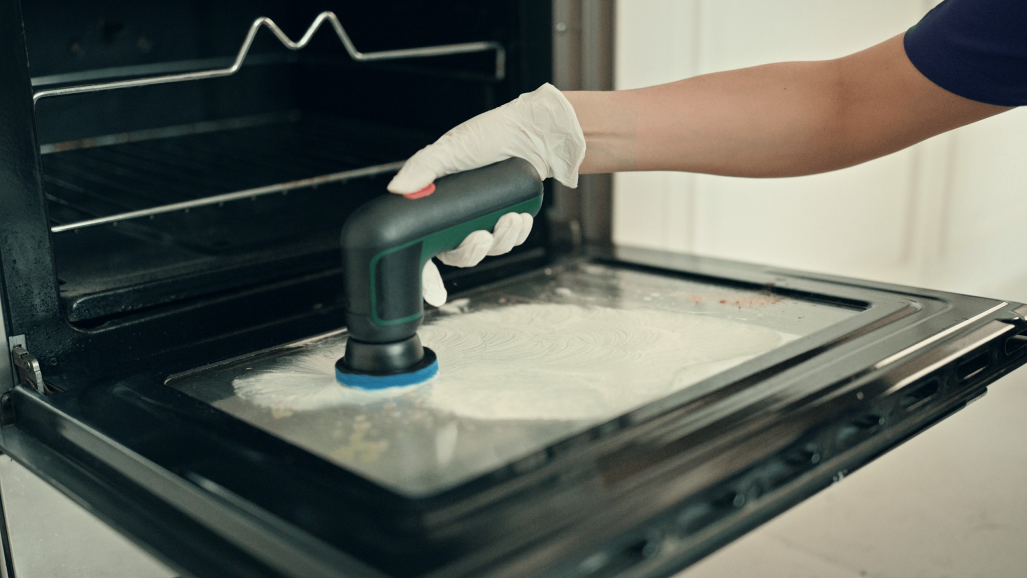 A person using a machine to polish the ovenDescription automatically generated